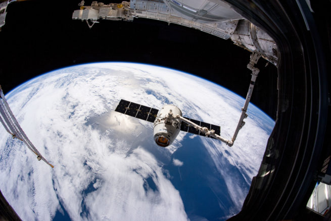 Vu depuis la fenêtre de la Station spatiale internationale: le bras Canadarm2 attrapant le vaisseau-cargo Dragon de SpaceX. (Source : NASA/Anne McClain.)