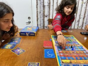 Deux jeunes qui jouent assis à une table au jeu de société dragons et échelles.